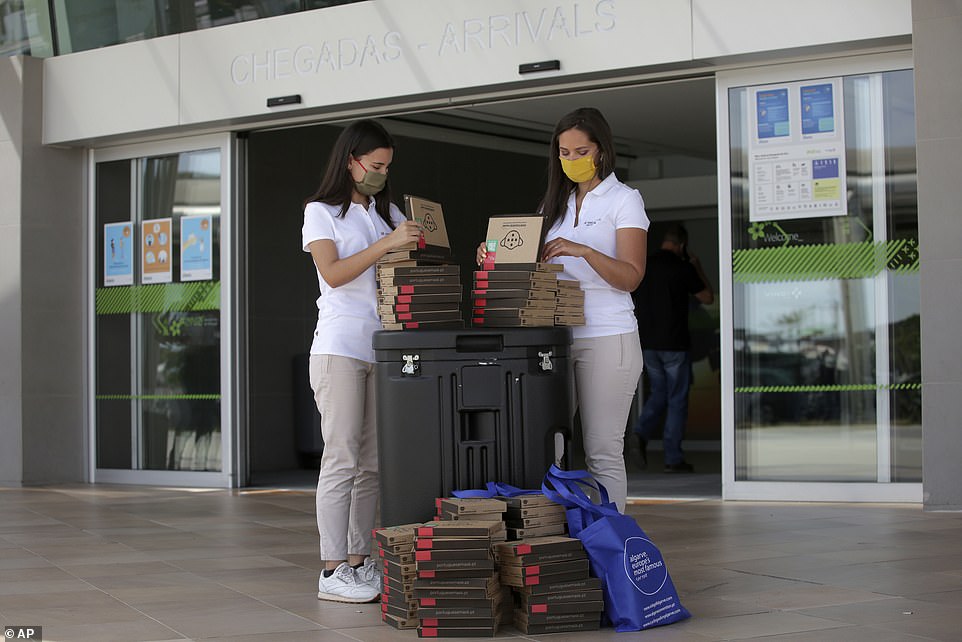 Algarve tourism authority workers prepare Covid-19 welcome kits containing masks and disinfectant to hand out to passengers arriving at Faro airport