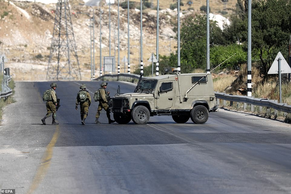 Israeli soldiers close to the scene of the shooting outside the West Bank city of Hebron on Wednesday