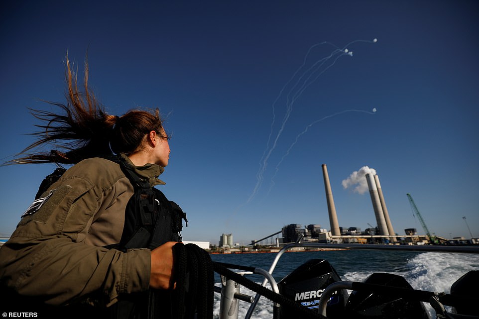 An Israeli soldier looks on as Israel's Iron Dome anti-missile system intercept rockets launched from the Gaza Strip towards Israel, as it seen from a naval boat patrolling the Mediterranean Sea off the southern Israeli coast as Israel-Gaza fighting rages on Tuesday